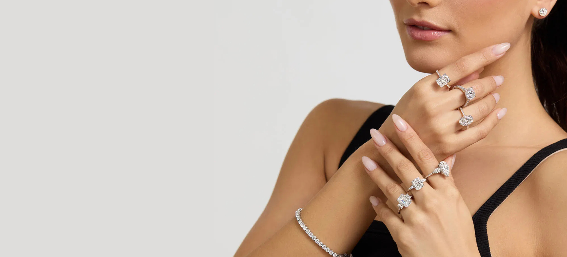 Woman wearing multiple diamond rings on a plain background