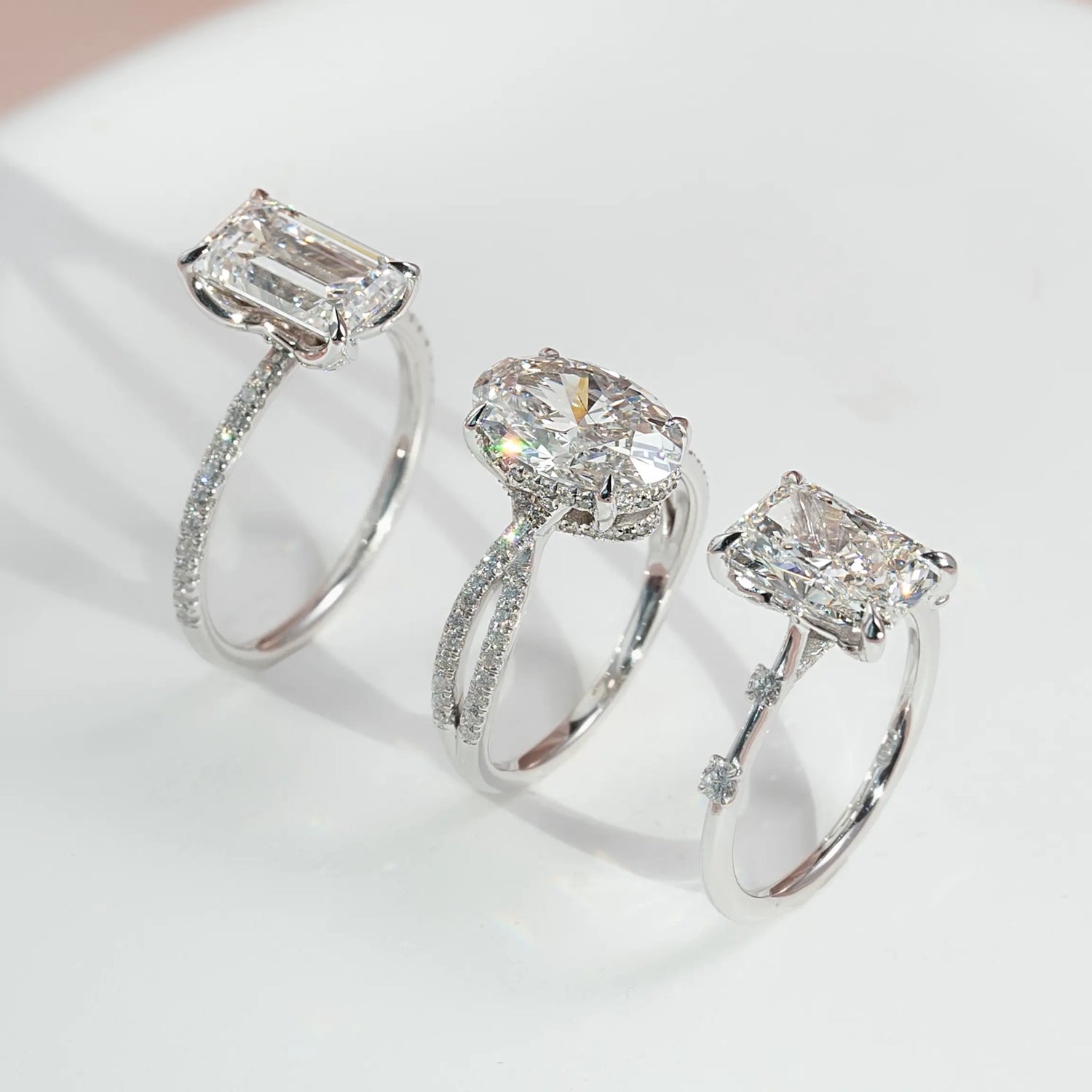 Three White gold diamond Engagement rings on a light background